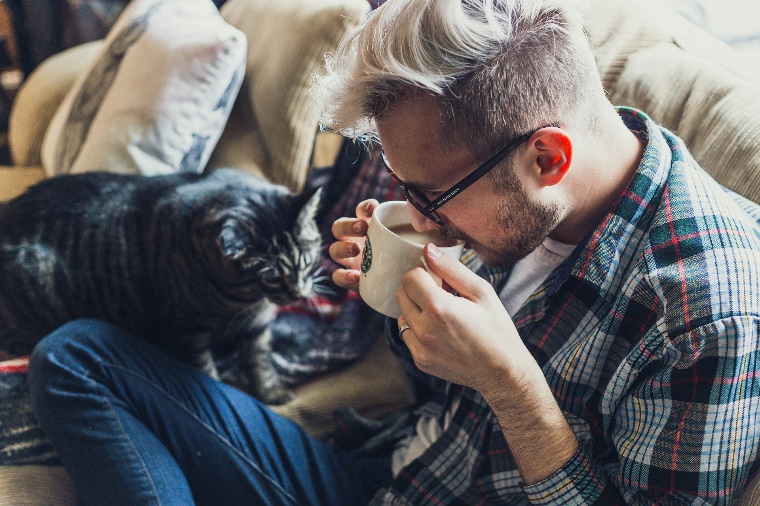 A person drinking from a cup with a cat on his lap

Description automatically generated with medium confidence